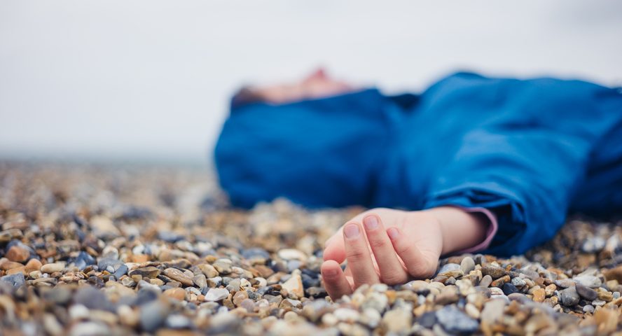 A woman faints on a beach.